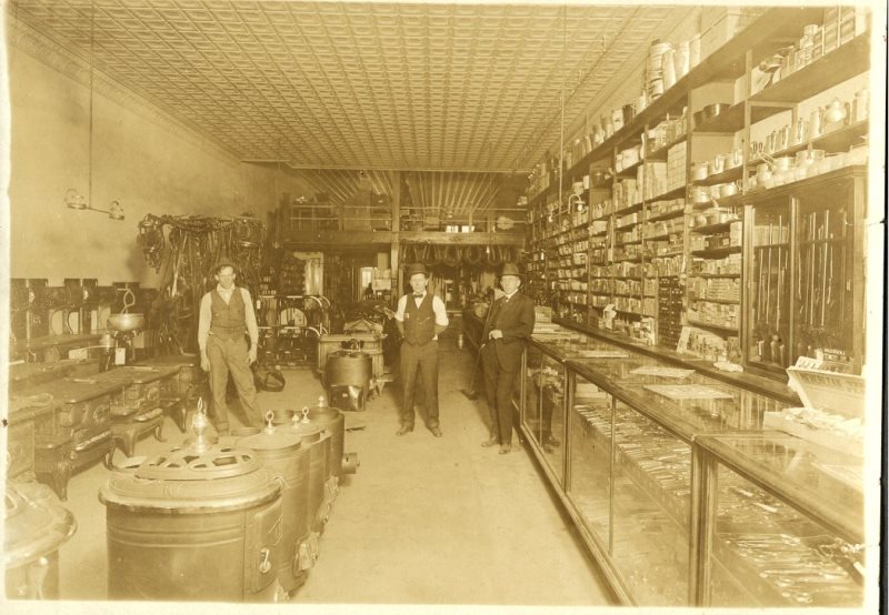 Sepia photo of old porter goods store with people inside