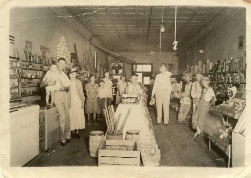 Sepia photo of old porter goods store with people inside
